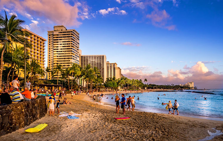 Tourists on the beach front at sunset on Waikiki beach ©Jeff Whyte/Shutterstock