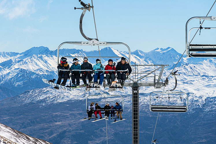 Skier and snowboarder ride a chairlift in the Remarkables ski resort in New Zealand ©AsiaTravel/Shutterstock