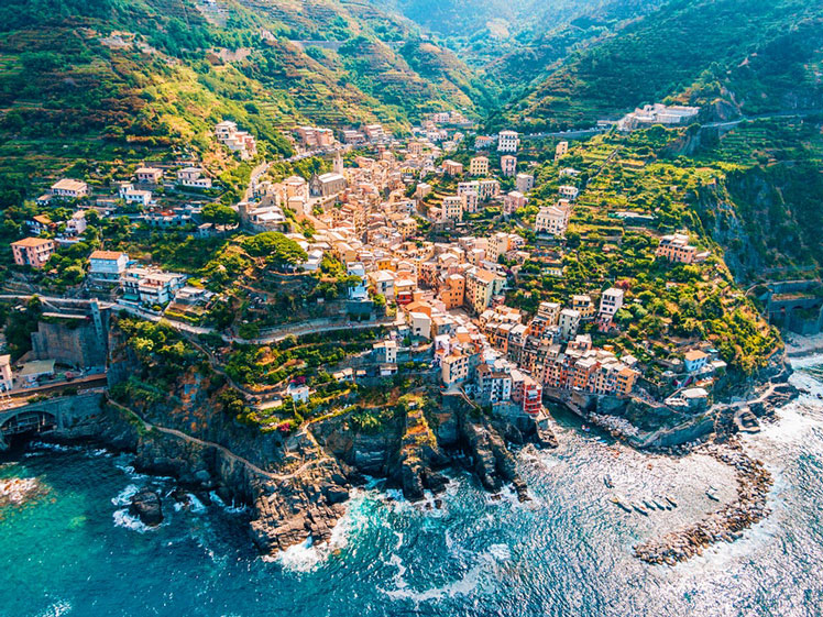 Aerial view of town in mountains towering over tranquil sea Cinque Terre SimonSkafar / Getty Images